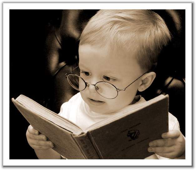 A baby reading a book with glasses.